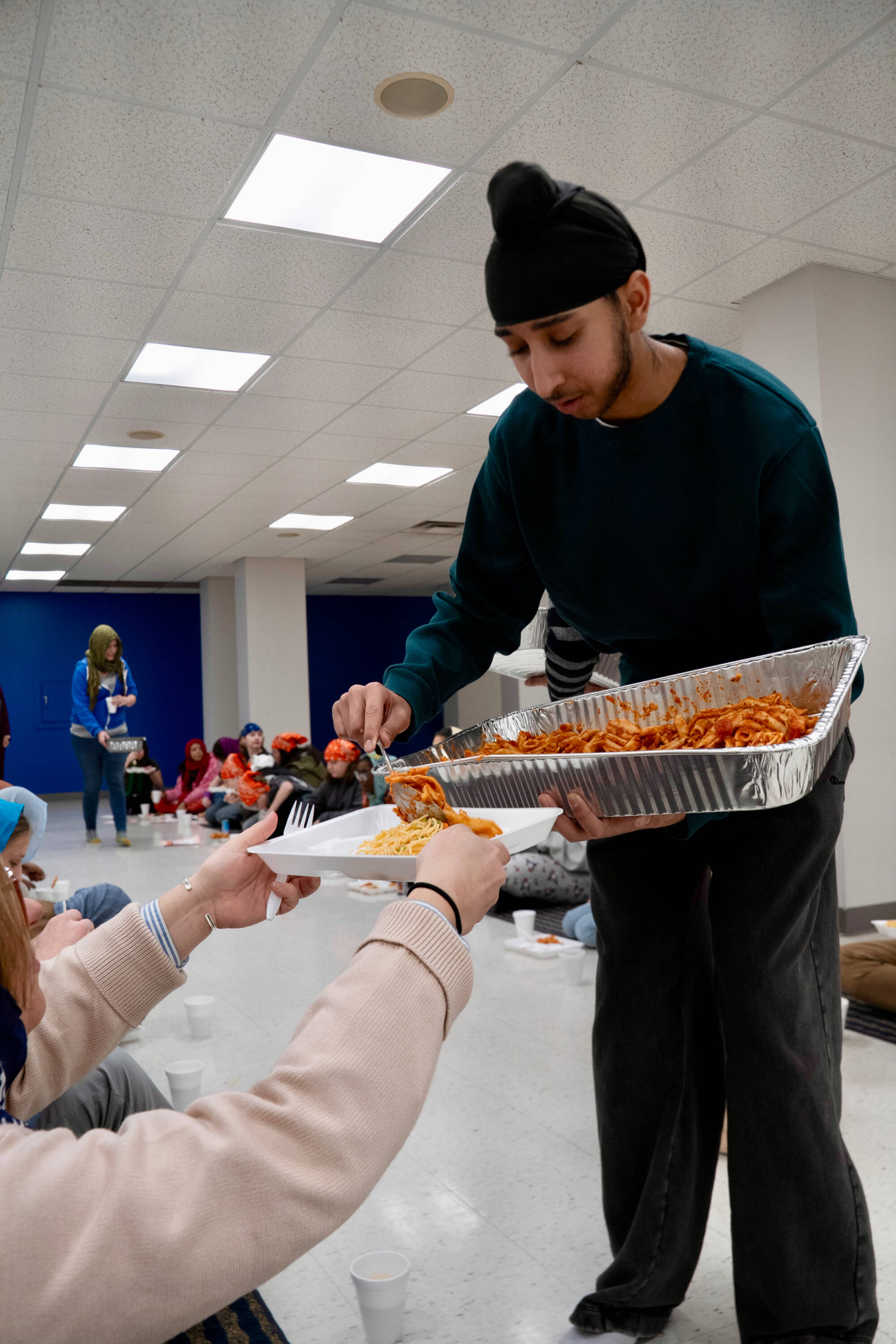 A young Sikh man serving food to students.